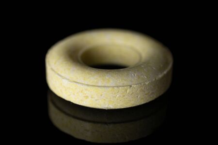 One whole round pale yellow candy isolated on black glassの写真素材