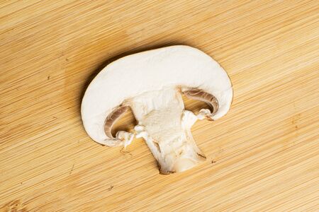 One slice of fresh brown mushroom champignon flatlay on light woodの写真素材