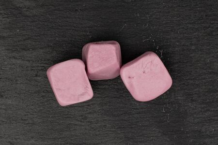 Group of three whole soft pastel candy flatlay on grey stone