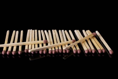 Lot of whole brown safety match in row isolated on black glassの写真素材