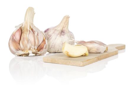 Group of two whole two pieces of aromatic white garlic on wooden cutting board isolated on white backgroundの写真素材