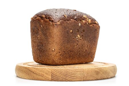 One whole fresh baked dark bread on bamboo plate isolated on white background
