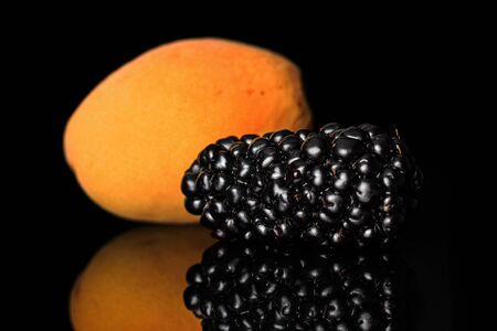 Group of two whole fruits apricot and blackberry isolated on black glassの写真素材