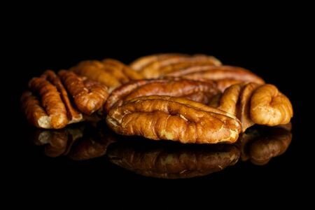 Lot of whole dry brown pecan nut isolated on black glass