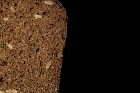 One half of fresh baked dark bread isolated on black glassの写真素材