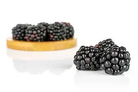Lot of whole fresh black blackberry on bamboo coaster isolated on white background
