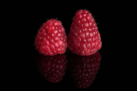 Group of two whole fresh red raspberry isolated on black glassの写真素材