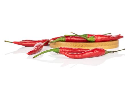 Lot of whole hot red chili on round bamboo coaster isolated on white background