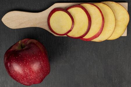 Group of one whole five slices of fresh apple red delicious on wooden cutting board flatlay on grey stoneの写真素材