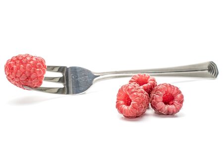 Group of four whole fresh crimson raspberry with steel fork isolated on white backgroundの写真素材