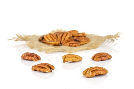 Lot of whole dry brown pecan nut on natural sackcloth isolated on white background