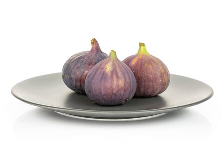 Group of three whole fresh purple fig on gray ceramic plate isolated on white backgroundの写真素材