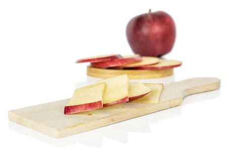 Group of one whole seven slices of fresh apple red delicious on round bamboo coaster on wooden cutting board isolated on white backgroundの写真素材