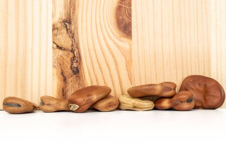 Lot of whole fresh brown bean vicia faba with wood behind isolated on white backgroundの写真素材