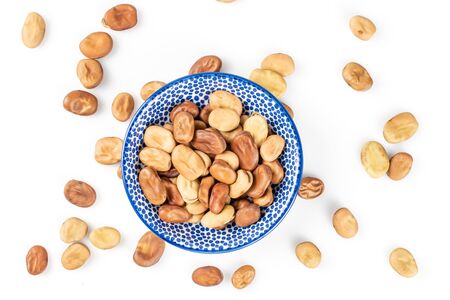 Lot of whole fresh brown bean vicia faba with ceramic saucer flatlay isolated on white backgroundの写真素材
