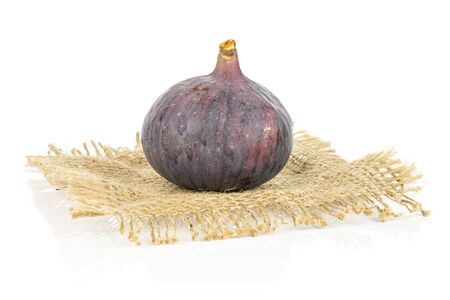 One whole fresh purple fig on natural sackcloth isolated on white backgroundの写真素材