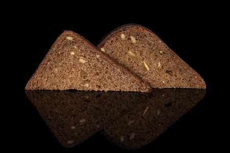 Group of two slices of fresh baked dark bread isolated on black glass