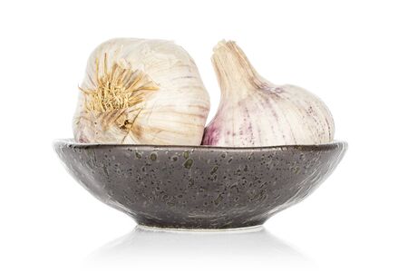 Group of two whole aromatic white garlic on glazed bowl isolated on white backgroundの写真素材
