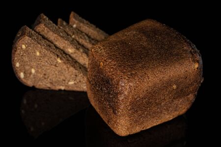 Group of one whole four slices of fresh baked dark bread on black glassの写真素材