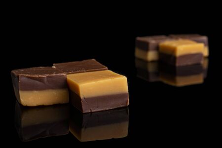 Group of six whole sweet brown caramel chocolate candy in two groups isolated on black glassの写真素材