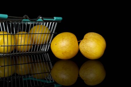 Group of five whole fresh yellow plum in shopping basket isolated on black glass