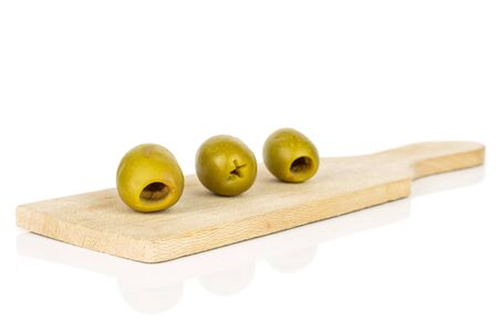 Group of three whole pitted green olive on small wooden cutting board isolated on white backgroundの写真素材