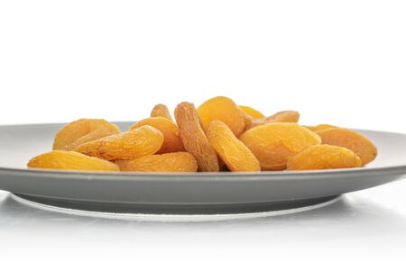 Lot of whole dried orange apricot heap in glazed bowl isolated on white backgroundの写真素材