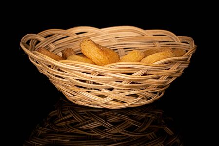 Lot of whole dried orange apricot in round rattan bowl isolated on black glass