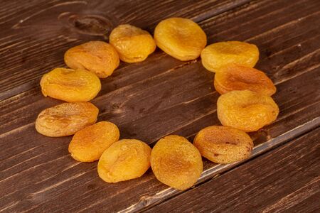 Lot of whole dried orange apricot in circle on brown woodの写真素材