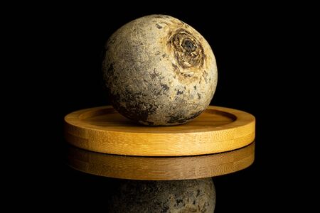 One whole raw red beetroot on bamboo coaster isolated on black glassの写真素材