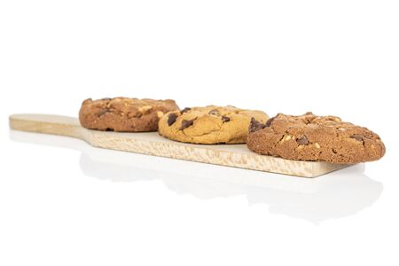 Group of three whole sweet brown cookie on wooden cutting board isolated on white background