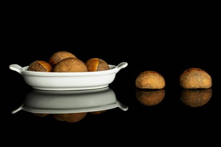 Group of six whole sweet brown chestnut in white oval ceramic bowl isolated on black glass