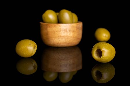 Group of six whole pitted green olive in tiny wooden bowl isolated on black glassの写真素材