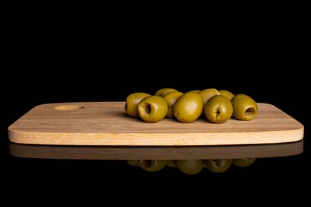 Lot of whole pitted green olive on bamboo cutting board isolated on black glassの写真素材