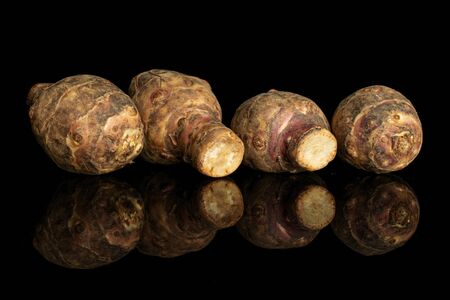 Group of four whole fresh brown jerusalem artichoke isolated on black glassの写真素材