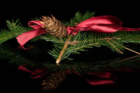 Lot of whole decorated christmas green branch spruce with red ribbon isolated on black glassの写真素材