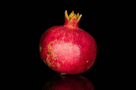 One whole fresh red pomegranate isolated on black glassの写真素材