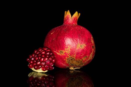 Group of one whole one piece of fresh red pomegranate isolated on black glassの写真素材