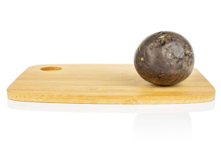 One whole sweet dark purple passion fruit on bamboo cutting board isolated on white backgroundの写真素材
