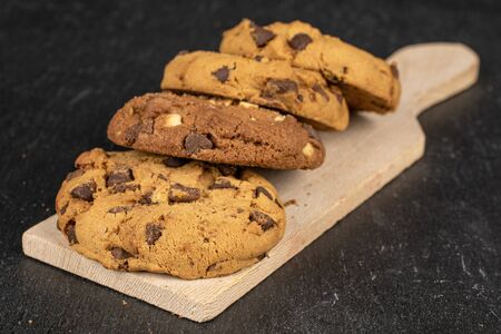 Group of four whole sweet brown cookie on wooden cutting board flatlay on grey stoneの写真素材