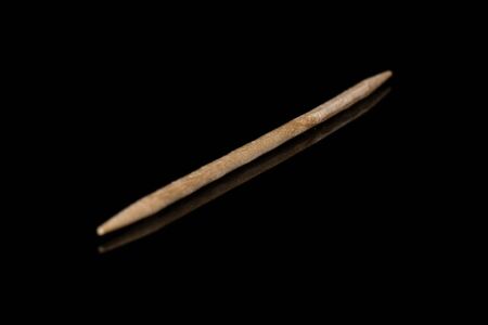 One whole wooden brown toothpick isolated on black glassの写真素材