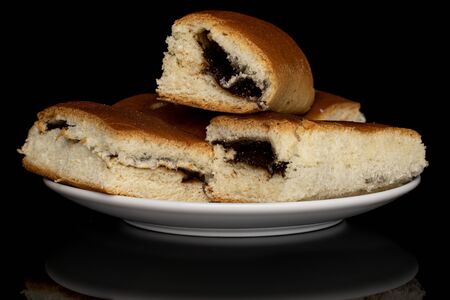 Group of four whole sweet czech bun on white ceramic plate isolated on black glassの写真素材