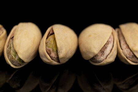 Group of five whole salted pistachio isolated on black glassの写真素材