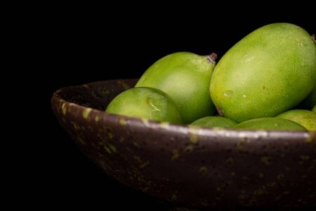 Lot of whole hardy green kiwi closeup in glazed bowl isolated on black glassの写真素材