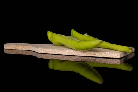 Group of two halves of hot green pepper banana on wooden cutting board isolated on black glassの写真素材