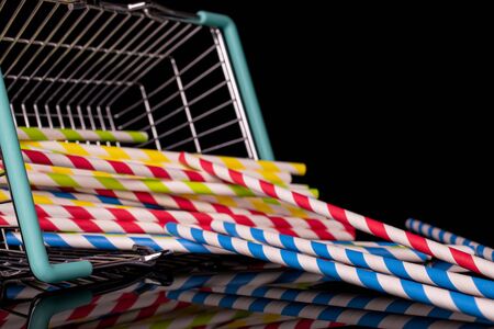 Lot of whole dump paper straw in shopping basket isolated on black glass