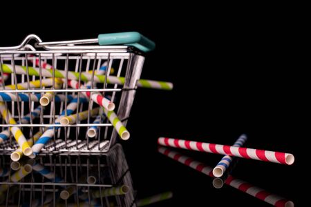 Lot of whole arranged paper straw in shopping basket isolated on black glassの写真素材