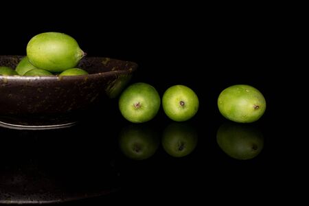Lot of whole hardy green kiwi in glazed bowl isolated on black glassの写真素材