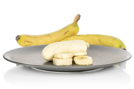 Group of two whole one half four slices of sweet yellow banana on gray ceramic plate isolated on white backgroundの写真素材
