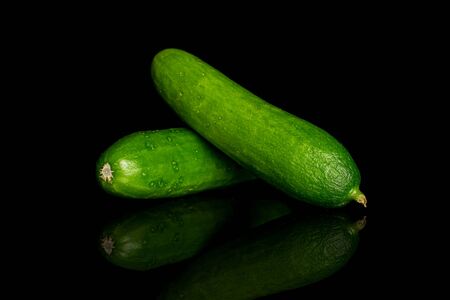 Group of two whole fresh green baby cucumber isolated on black glassの写真素材